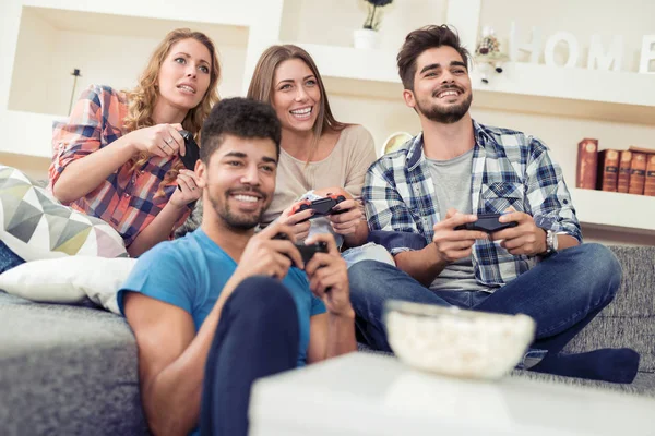 Amici sorridenti che giocano ai videogiochi a casa — Foto Stock