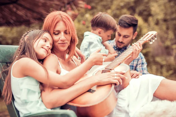 Happy young family playing guitar together and laughing — Stock Photo, Image