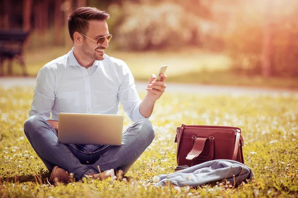 Молодий чоловік використовує ноутбук у парку — стокове фото
