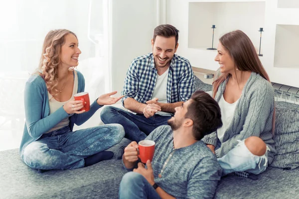 Друзья сидят на диване и пьют кофе — стоковое фото