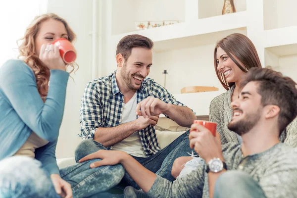 Группа молодых людей, сидящих и улыбающихся с кофе — стоковое фото