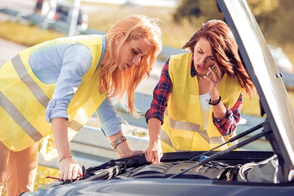 To jenter på veien prøver å fikse bilen sin – stockfoto