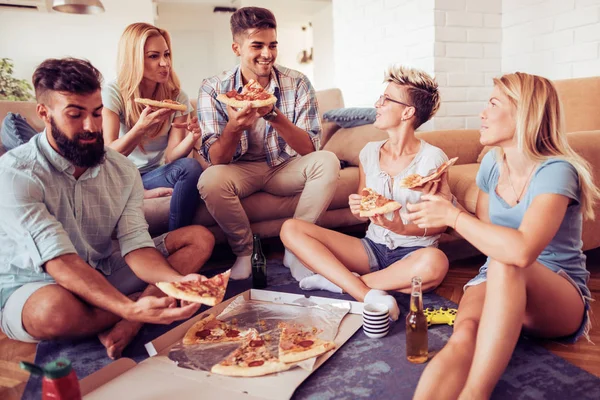 Счастливые друзья едят пиццу дома — стоковое фото