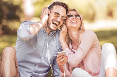 Genç çift sakin ve akıllı telefon müzik dinlemek.