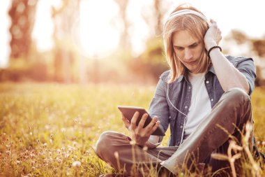 Tablet ve kulaklık ile genç adam.