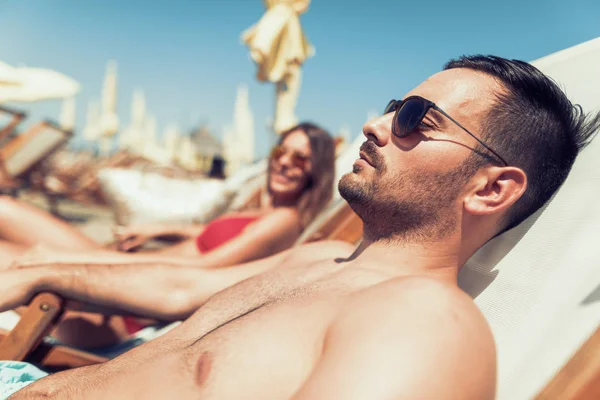 Feliz joven pareja en sillas en la playa de verano —  Fotos de Stock