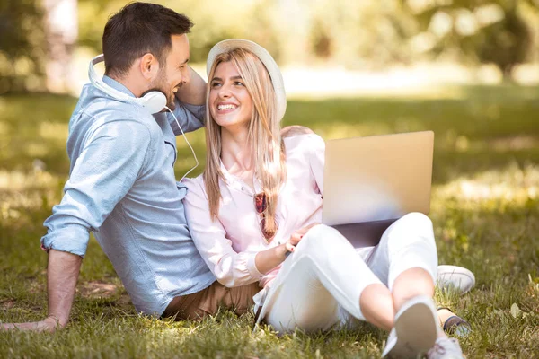 Junges verliebtes Paar mit Laptop im Frühlingsgarten. — Stockfoto