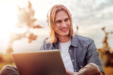 Parkta dizüstü bilgisayar kullanan genç adam