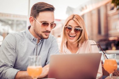 Genç çift dışarıda dizüstü bilgisayar kullanıyor. 