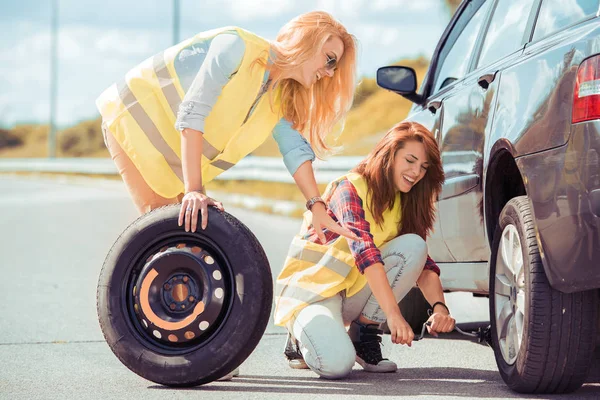 Жінки на дорозі змінюють шину — стокове фото