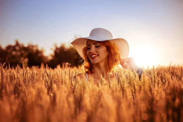 Lächelnde Frau auf dem Feld bei Sonnenuntergang. — Stockfoto