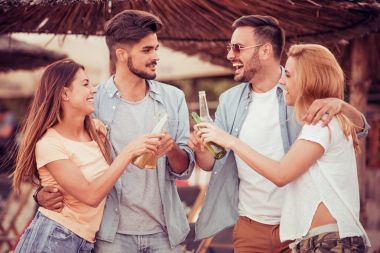 Gençler kumsalda bira içmek