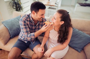 Mutlu çift kanepede pizza yemek