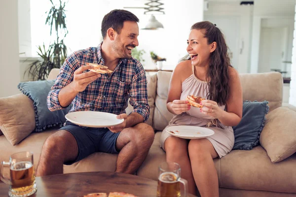 Счастливая пара ест пиццу на диване — стоковое фото