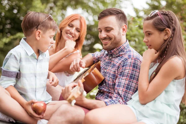 Father playing guitar in garden — Stock Photo, Image