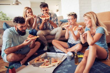 Arkadaşlar evde pizza yiyorlar.