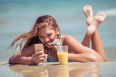 Kumsalda akıllı telefon kullanan kadın