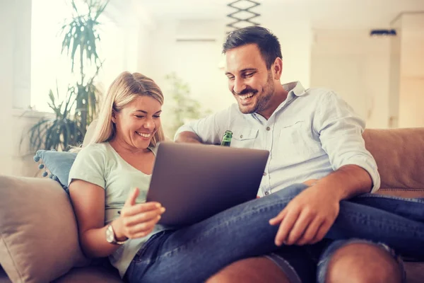 Pareja riendo en sofá con portátil — Foto de Stock