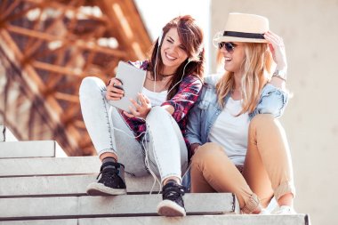 Merdivenlerde tablet ile oturan kızlar