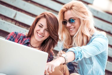 Kızlar merdivenlerde oturan dizüstü bilgisayar ile