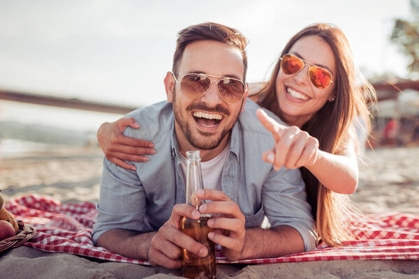 Couple lying on beach with beer