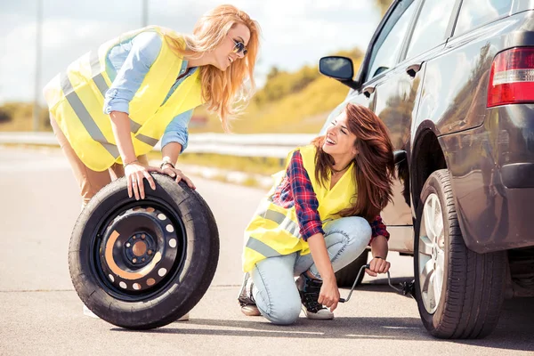 Meninas mudando de roda em carro quebrado — Fotografia de Stock