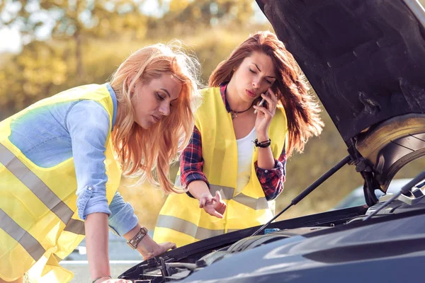 Две девушки смотрят под капот машины — стоковое фото