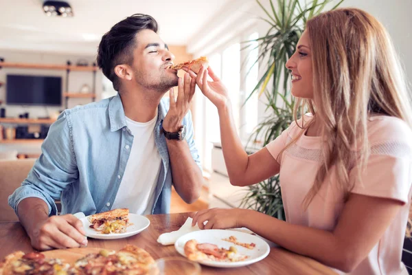 Пара ест пиццу дома — стоковое фото