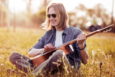 Adam akustik gitar çalıyor.