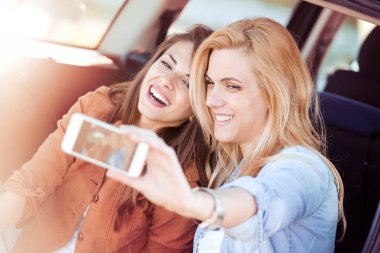 Gülümseyen kızlar selfie çekiyor.