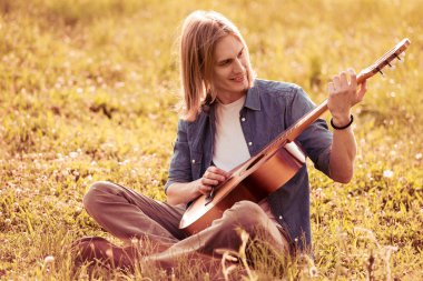 Adam akustik gitar çalıyor.