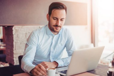  Genç adam ofiste dizüstü bilgisayarla çalışıyor..