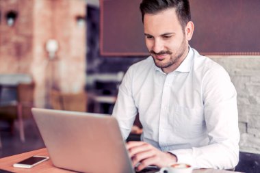  Genç adam ofiste dizüstü bilgisayarla çalışıyor..