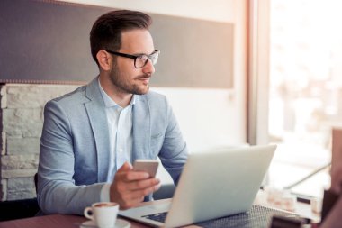 Genç işadamı ofiste çalışıyor, masada oturuyor..