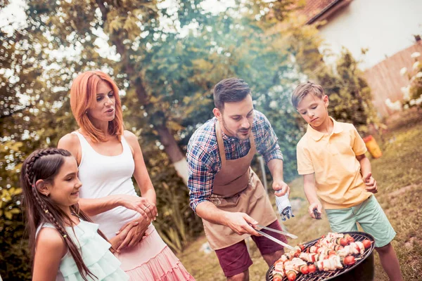 Feliz jovem família churrasco carne na grelha . — Fotografia de Stock