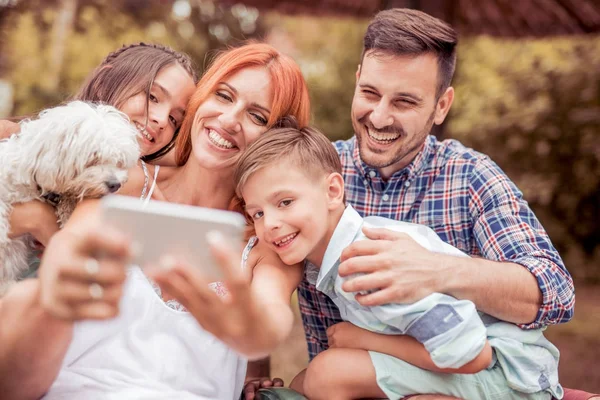 Sonriente joven familia tomando selfie en el parque . — Foto de Stock