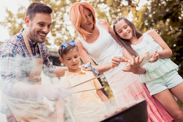 Happy young family barbecuing meat on the grill. — Stock Photo, Image