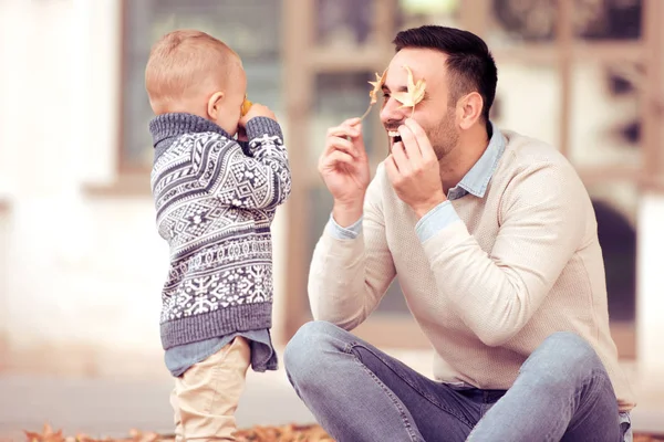 Vater und Sohn spielen im Herbstpark mit Blättern — Stockfoto