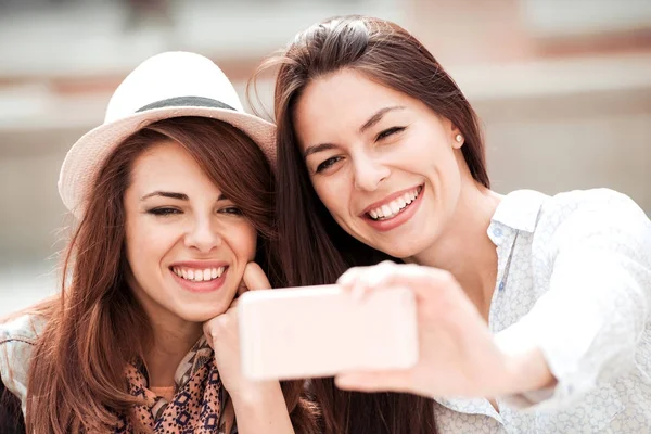 Duas meninas sorrindo usando telefone inteligente em um café . — Fotografia de Stock