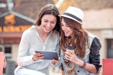  Tablet kullanma ve gülümseyen iki güzel genç kadın.