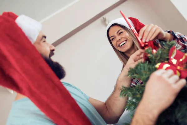 Feliz pareja decorando el árbol de Navidad en su casa —  Fotos de Stock