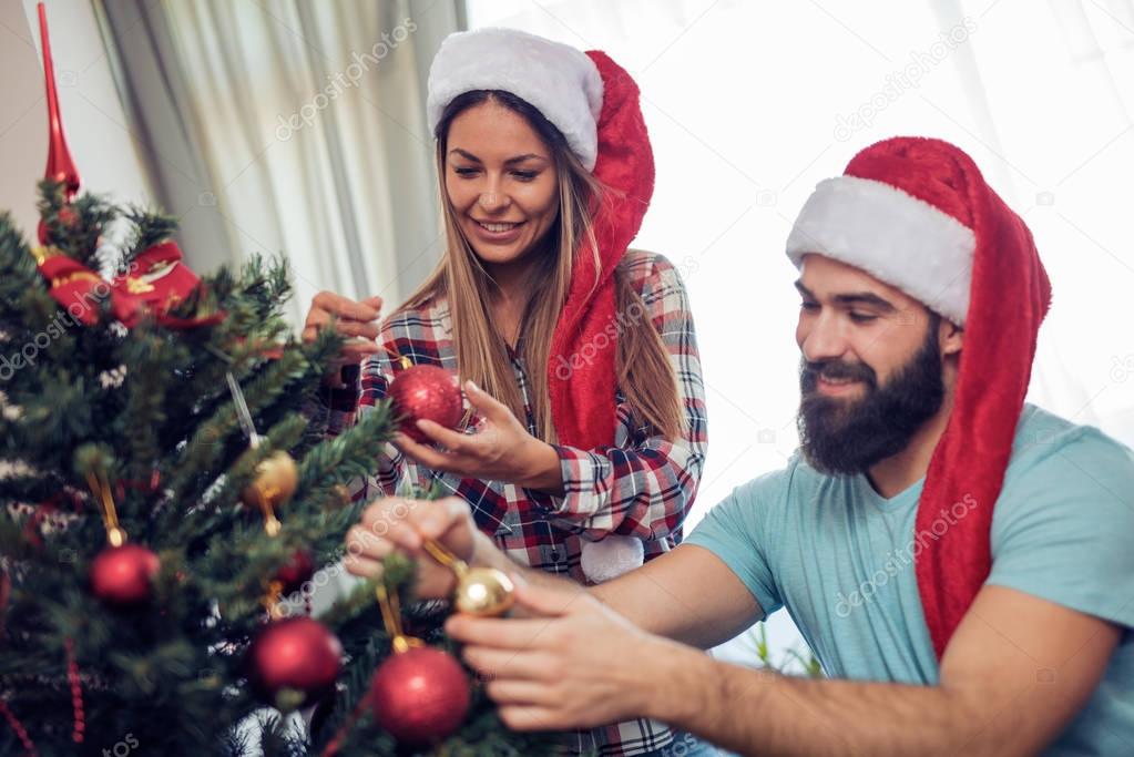 Happy couple decorating Christmas tree in their home