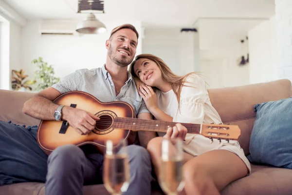 Mann mit Akustikgitarre singt für lächelnde Frau. — Stockfoto