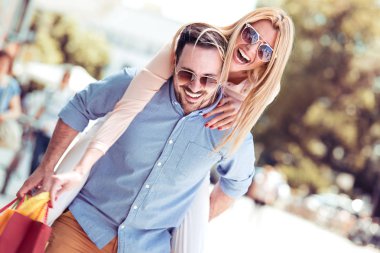 Sırtlama arkasında onun kız arkadaşı alışveriş bir gün sonra şehirde taşıyan veren adam. Genç neşeli çift resmini.