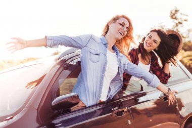 Sevinç dolu. Ellerini tutarak ve mutlu hissederken araba sürüş mutlu genç çekici kızlar