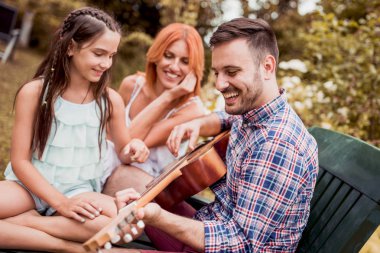 Mutlu bir aile. Genç Baba, anne, oğlu ve kızı birlikte gitar çalmak. Genç anne çocukları için gitar çalmak.