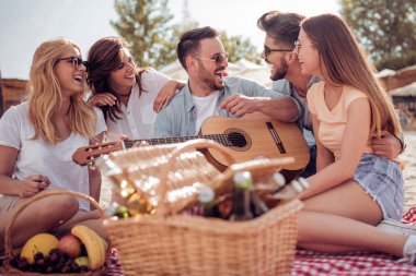 kumsalda oturuyor ve gitar çalmak eğleniyor arkadaşlar