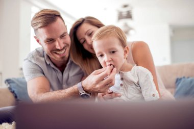 Kanepede oturan ve film izlerken patlamış mısır yemek yetişkin çift.