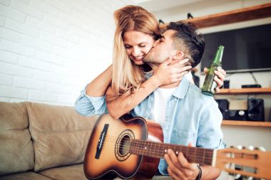 Romantik Çift eğleniyor gitar ile evde oturan.