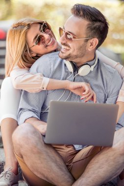 Genç çift merdivenlerde bir dizüstü bilgisayar ile ilgili bir video izlemek. Gülüyorlar, komik video görmek.